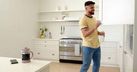 Young man pouring coffee into cup in modern minimalist kitchen