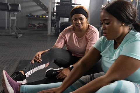 African american women stretching together in gym partner workout and motivational coaching