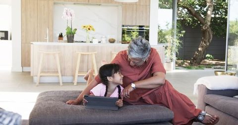 Grandmother Bonding with Granddaughter Using Tablet, Modern Home