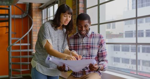 Collaborative Team Analyzing Blueprints in Modern Office Space
