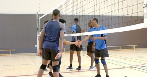 Diverse male volleyball teams shaking hands at net showing sportsmanship and team respect