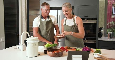 Senior Couple Cooking with Fresh Vegetables in Modern Kitchen