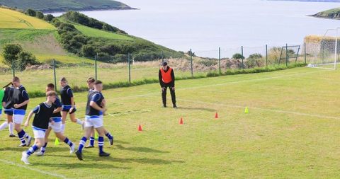 Teenage Soccer Team Training with Coach on Coastline