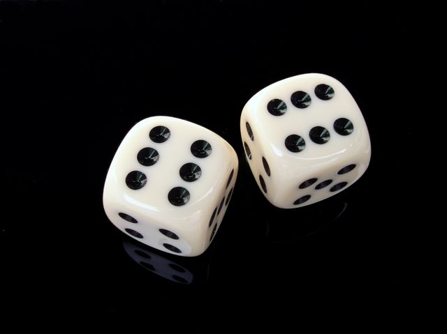 Image depicting a pair of white dice with black dots on a black background. Dice are showing a five and six on top. Ideal for use in materials related to gaming, gambling, board games, and probability studies. Great for advertising casinos, promoting game nights, or illustrating concepts of chance and luck.