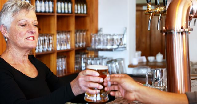 Senior Woman Bartender Serving Beer at a Bar - Download Free Stock Images Pikwizard.com
