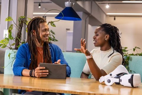 Discussing VR project in bright coworking space with tablet and VR headset