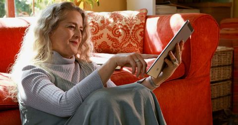 Senior Woman Using Tablet in Cozy Living Room Setting