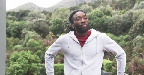 Contemplative African American Man Wearing Gray Hoodie Gazing at Mountains on Balcony