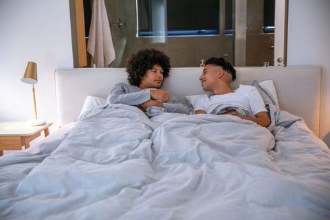 Two men relaxing in bed sharing conversation