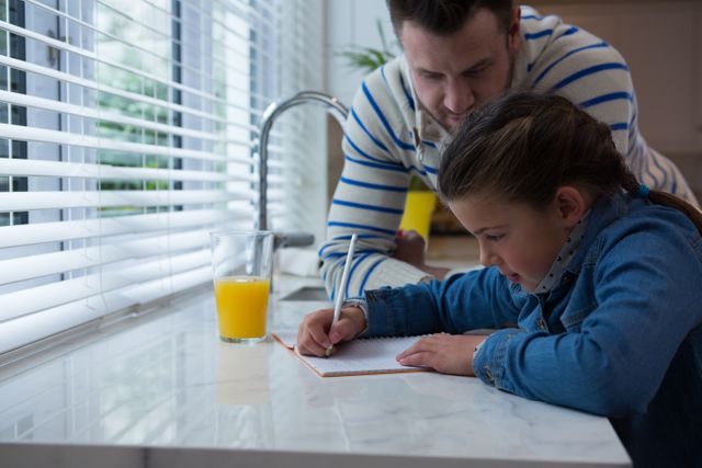 Father assisting daughter in her studies in kitchen