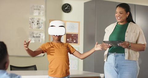 African woman teacher guiding student using vr headset in interactive classroom