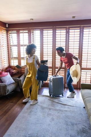 Young black women packing luggage and backpack, heading out on sunny weekend vacation