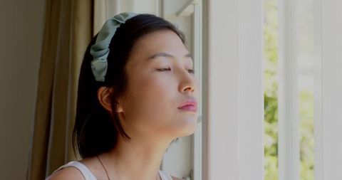 Woman with headband by window savoring peaceful moment