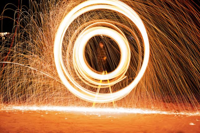Long exposure light trails forming intricate circular patterns against a dark background. Ideal for illustrating concepts of motion, energy, creativity, and night photography. Good for backgrounds, artistic projects, wallpapers, and light art design ideas.