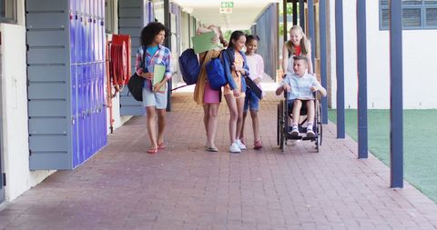 Inclusive group of schoolchildren walking together in corridor