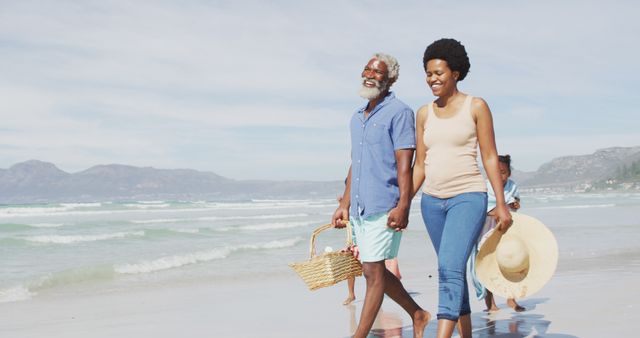 Happy african american couple walking with children on sunny beach. healthy and active time beach holiday.