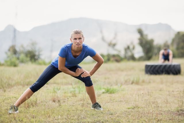 Fit woman stretching in outdoor boot camp. Ideal for promoting fitness programs, outdoor exercise routines, healthy lifestyle campaigns, and athletic wear advertisements.
