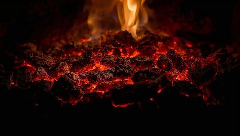 Glowing embers and charred coal emitting intense red heat with flickering flame