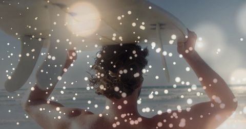 Back View of Surfer with Surfboard on Beach at Sunset