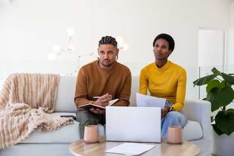 Diverse Couple Reviewing Documents on Sofa in Modern Living Space