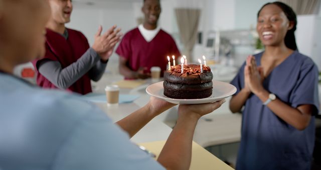 Diverse male and female doctors celebrating birthday at reception desk at hospital. Medicine, healthcare, teamwork, birthday, hospital and work, unaltered.