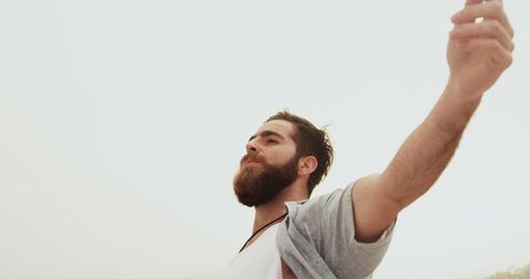 Serene Bearded Man Enjoying Freedom with Open Arms on Beach