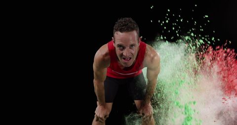 Male athlete resting amidst explosive color burst