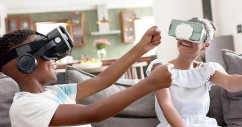 Joyful Siblings Enjoying Virtual Reality Gaming on Sofa