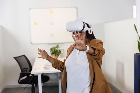 African American woman testing VR headset and checking smartwatch in modern office