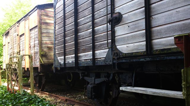 Old wooden freight train cars standing on rusted tracks evoke a sense of industrial history and nostalgia. Ideal for use in vintage industrial projects, historical transportation themes, and retro-themed designs. Captures rustic, vintage charm and can also be used in educational contexts highlighting the evolution of railway transport.