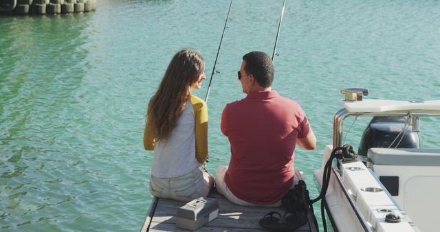 Caucasian father teaching happy teenage daughter fishing, sitting on jetty by boat on a sunny day. Leisure, free time, hobbies, family, travel and vacations.