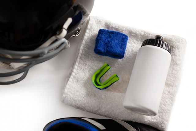 High angle view of wristband and bottle on napkin by sports helmet