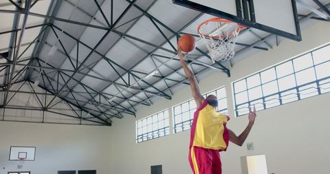 Basketball Player Shooting Powerful Dunk in Indoor Gymnasium
