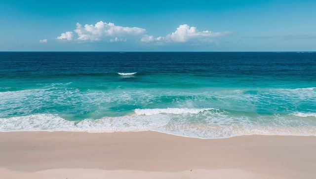 Turquoise Waves Rolling onto Pristine Sand under Blue Sky with Puffy Cumulus Clouds