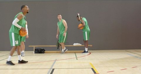 Multiracial basketball players preparing for practice in indoor gym during team warmup