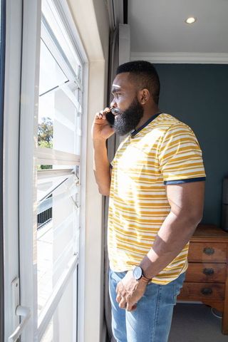 Mature Adult Using Smartphone by Sunlit Window at Home