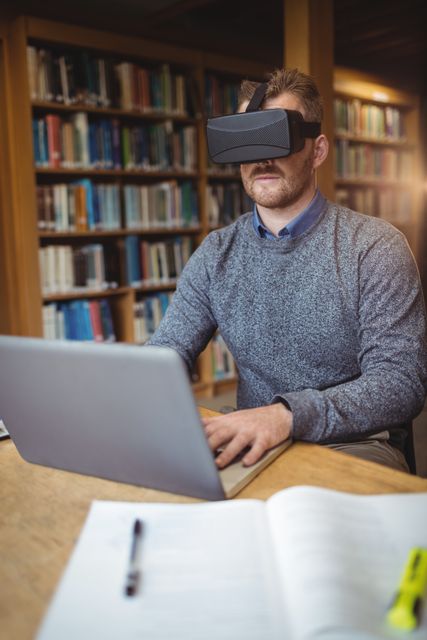 Mature student in virtual reality headset using laptop to help with studying at college library