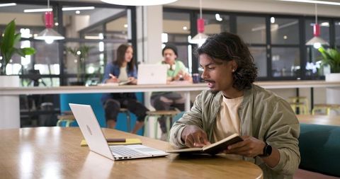 African American man working with laptop and notebook in bright modern coworking space