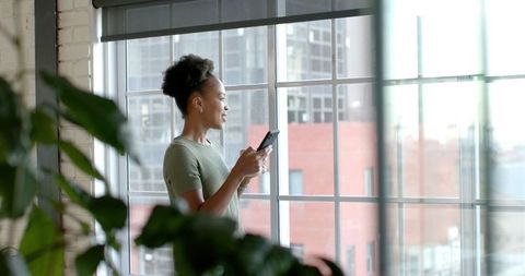 Businesswoman Holding Smartphone While Looking Out Office Window - Download Free Stock Images Pikwizard.com