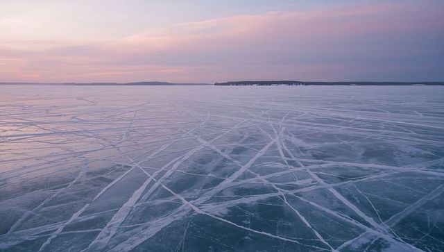 Serene Frozen Lake Crisscrossed by Intersecting Patterns at Dawn