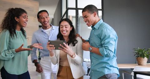Diverse Colleagues Celebrating Success with a Tablet in Modern Office