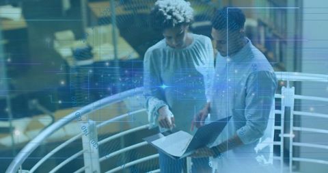 Coworkers collaborating over laptop in modern workspace