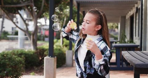 Child blowing bubbles on school campus showing joyous playtime