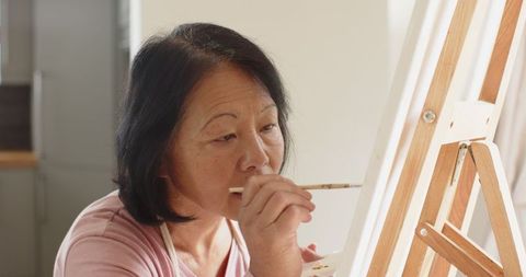 Senior woman pursuing painting as a creative hobby in home studio