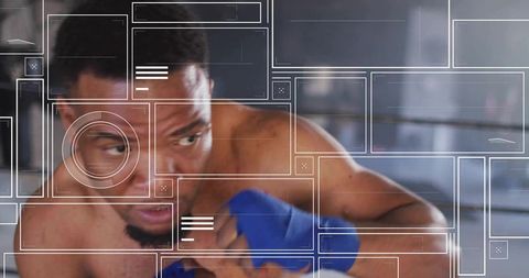 Focused male boxer training with blue hand wraps