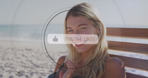 Woman at sandy beach enjoying warm climate and interacting digitally with social media overlays showing accumulated likes. Useful for illustrating social media influence, connectivity and vacation themes. Ideal for promotions of travel apps and media analytics solutions.