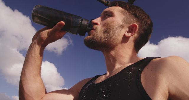 Man staying hydrated after an intense outdoor workout. Great for representing fitness, health, hydration, and active lifestyles.