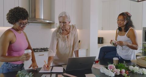 Multiracial women planning a wedding in modern kitchen
