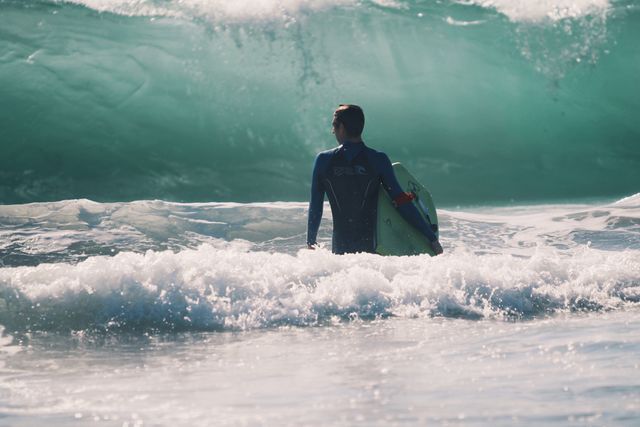 Surfer Standing in Ocean Facing Large Wave - Download Free Stock Photos Pikwizard.com