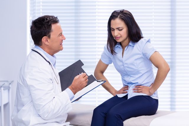 Doctor consulting a patient experiencing stomach pain in a clinic. Useful for illustrating medical consultations, healthcare services, patient care, and diagnosis of stomach-related issues.